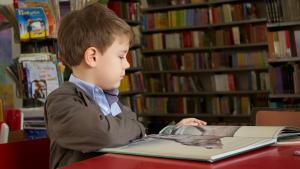 boy reading surrounded by books